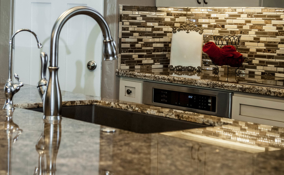 Example of a large transitional l-shaped dark wood floor eat-in kitchen design in Phoenix with an undermount sink, recessed-panel cabinets, white cabinets, granite countertops, multicolored backsplash, glass tile backsplash, stainless steel appliances and an island