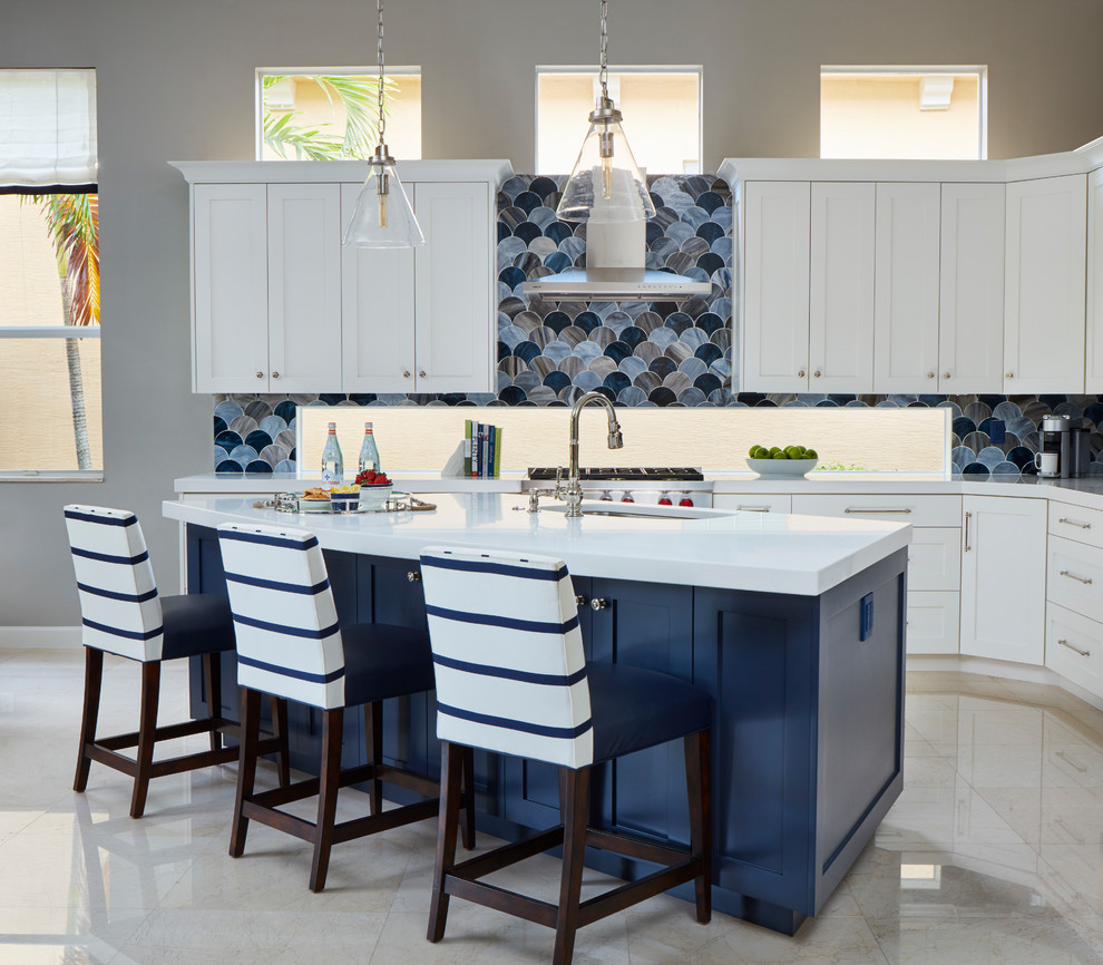 Photo of a large beach style l-shaped open plan kitchen in Miami with an undermount sink, shaker cabinets, white cabinets, blue splashback, glass tile splashback, stainless steel appliances, marble floors, with island and beige floor.