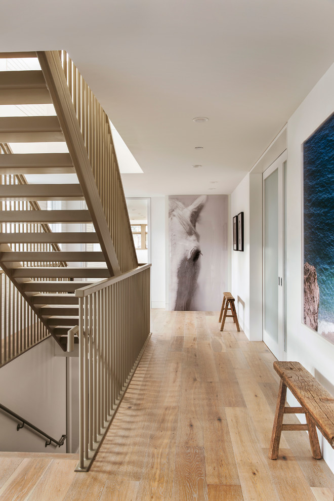 This is an example of a mid-sized beach style wood straight staircase in Los Angeles with open risers and metal railing.