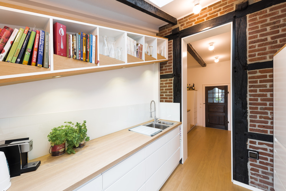 Geschlossene, Einzeilige, Mittelgroße Moderne Küche ohne Insel mit Einbauwaschbecken, Kassettenfronten, weißen Schränken, Arbeitsplatte aus Holz, Küchenrückwand in Weiß, Glasrückwand, weißen Elektrogeräten, hellem Holzboden, beigem Boden und beiger Arbeitsplatte in Sonstige