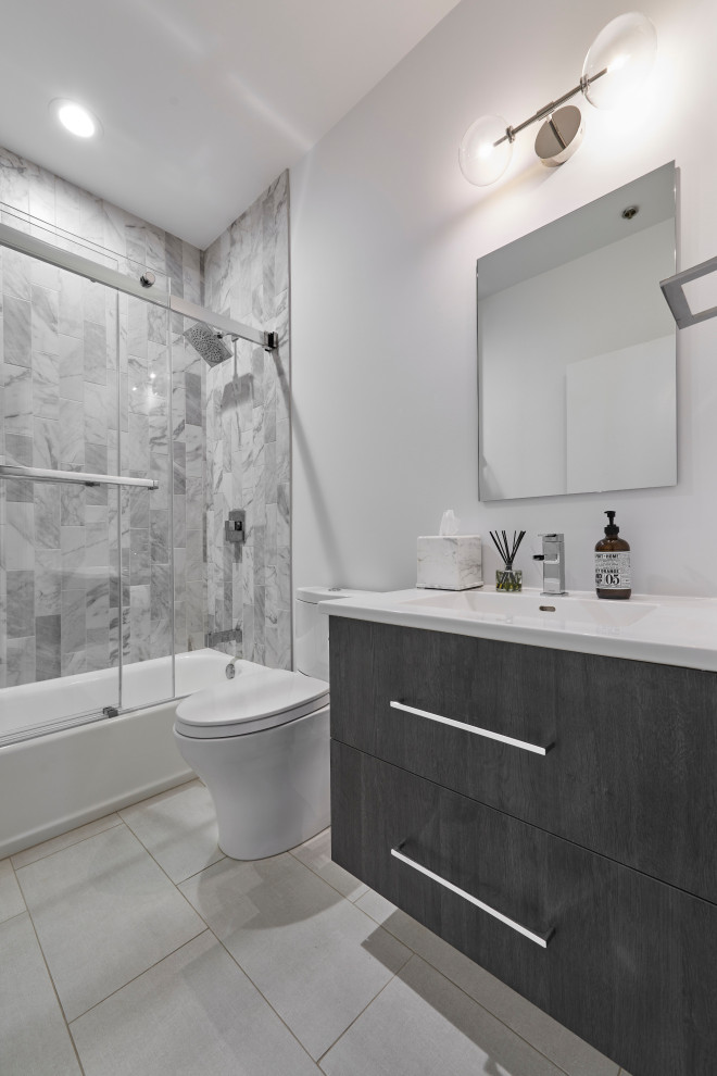 Modern inredning av ett mellanstort vit vitt en-suite badrum, med släta luckor, skåp i mörkt trä, ett badkar i en alkov, en dusch/badkar-kombination, en toalettstol med hel cisternkåpa, grå kakel, porslinskakel, vita väggar, klinkergolv i porslin, ett integrerad handfat, bänkskiva i kvartsit, grått golv och dusch med skjutdörr