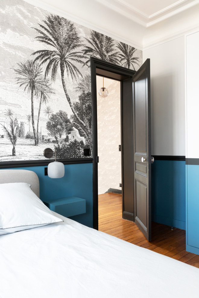 Diseño de dormitorio principal grande con paredes azules, suelo de madera clara, todas las chimeneas, marco de chimenea de piedra, suelo marrón y papel pintado