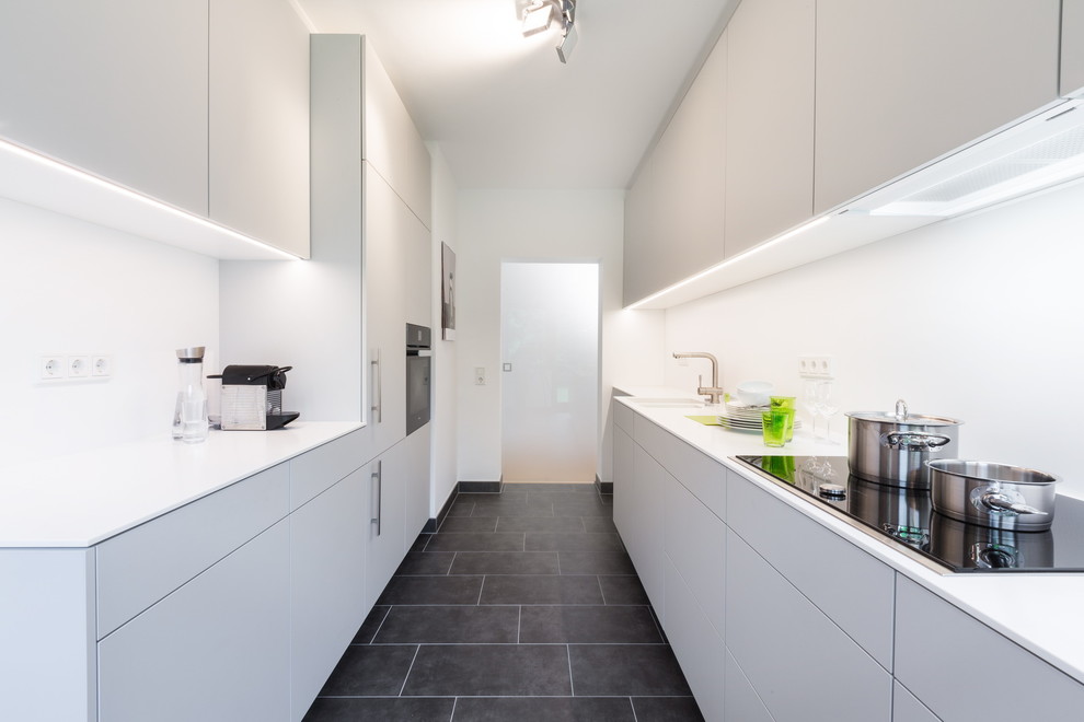 Inspiration for a mid-sized modern galley separate kitchen in Cologne with flat-panel cabinets, grey cabinets, solid surface benchtops, white splashback and no island.