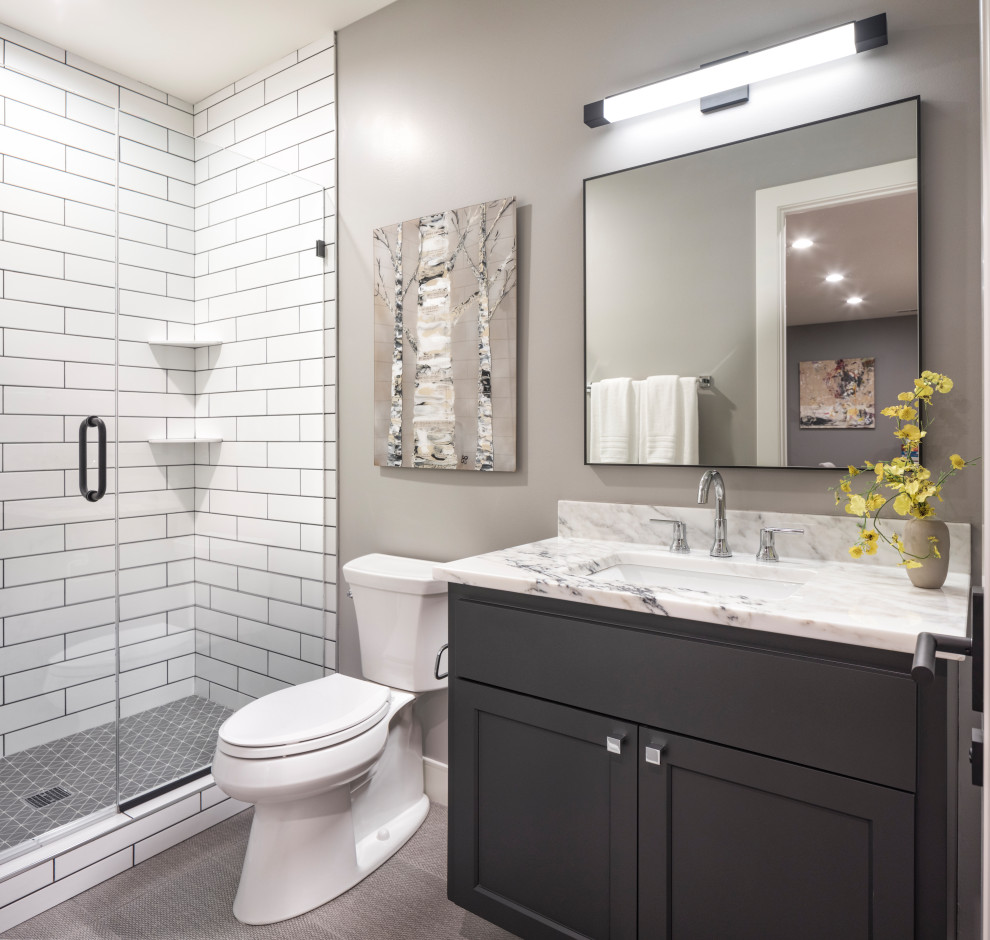 Inspiration for a large contemporary kids bathroom in Minneapolis with recessed-panel cabinets, black cabinets, an alcove shower, a one-piece toilet, blue tile, porcelain tile, grey walls, porcelain floors, an undermount sink, marble benchtops, grey floor, a hinged shower door and white benchtops.