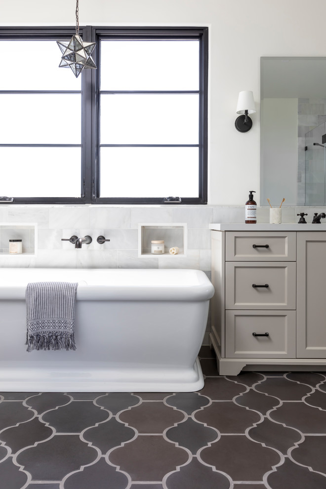 Inspiration for a mediterranean bathroom in Los Angeles with shaker cabinets, beige cabinets, a freestanding tub, white tile, white walls, brown floor and white benchtops.