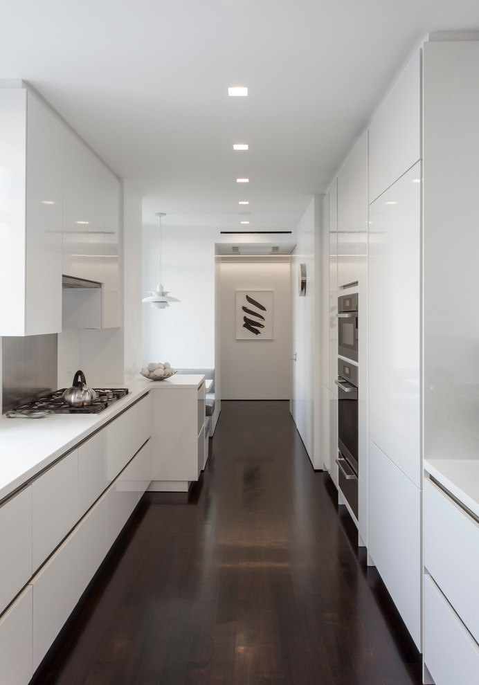 Contemporary galley kitchen in New York with flat-panel cabinets, white cabinets, dark hardwood floors and no island.