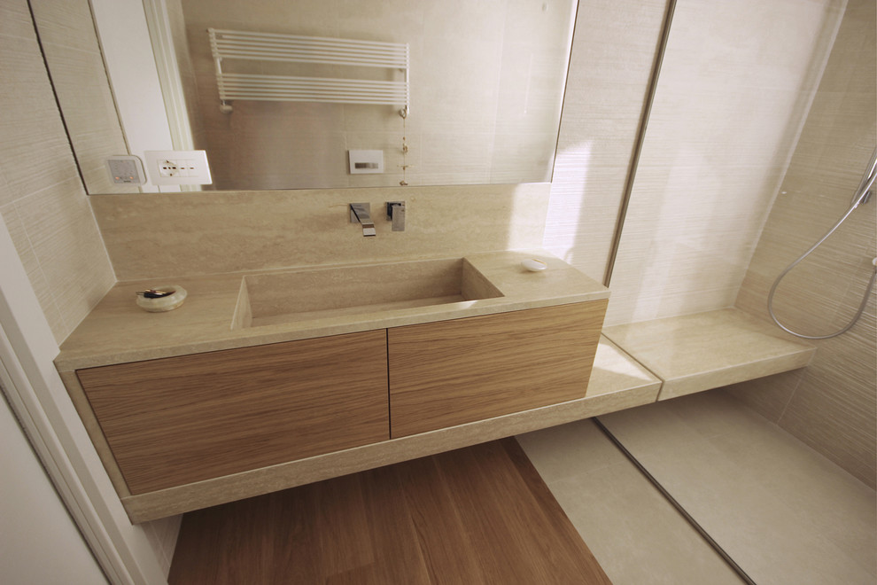 This is an example of a mid-sized modern 3/4 bathroom in Milan with flat-panel cabinets, light wood cabinets, a curbless shower, a wall-mount toilet, beige tile, porcelain tile, beige walls, medium hardwood floors, an integrated sink, marble benchtops, beige floor, an open shower and pink benchtops.