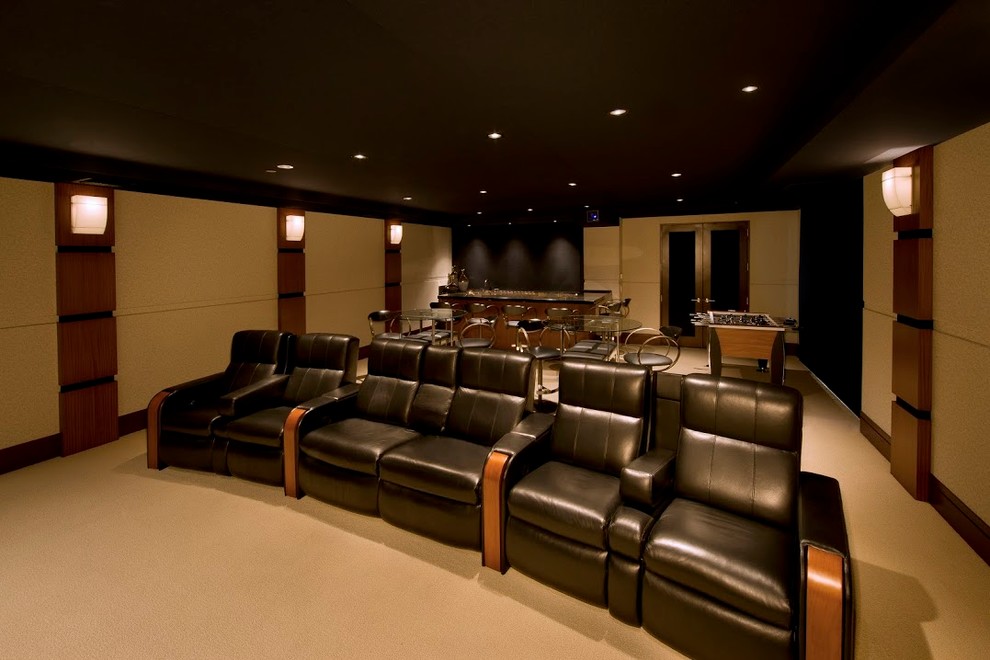 Photo of a large modern enclosed home theatre in Orange County with beige walls, carpet, a projector screen and beige floor.