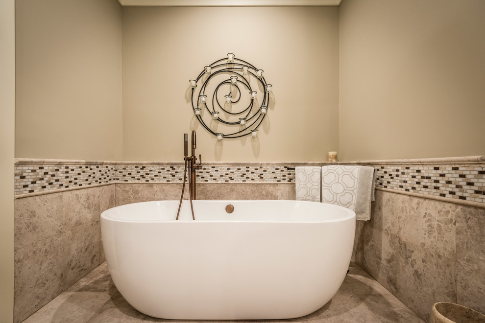 This is an example of a large traditional master bathroom in Charleston with beige cabinets, a freestanding tub, an alcove shower, beige tile, limestone, beige walls, limestone floors, an undermount sink, marble benchtops, beige floor, a hinged shower door, recessed-panel cabinets and a one-piece toilet.