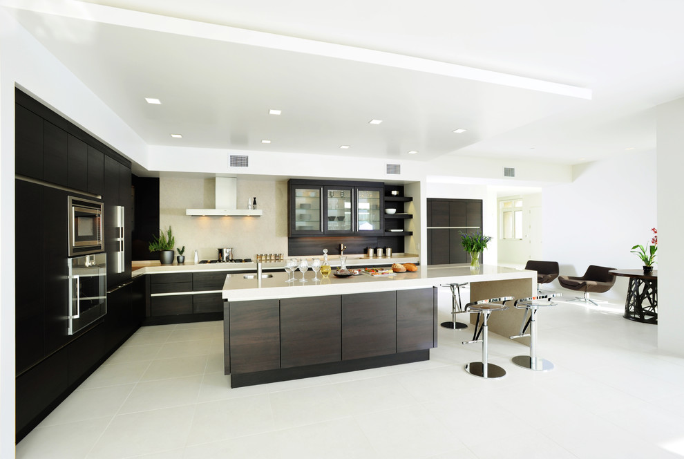 Large contemporary l-shaped open plan kitchen in San Francisco with flat-panel cabinets, dark wood cabinets, quartz benchtops, beige splashback, stone tile splashback, panelled appliances and with island.