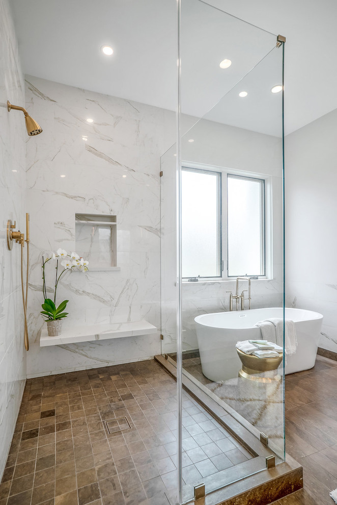 This is an example of a mid-sized contemporary bathroom in Los Angeles with a corner shower, white tile, a hinged shower door, a freestanding tub, white walls and brown floor.