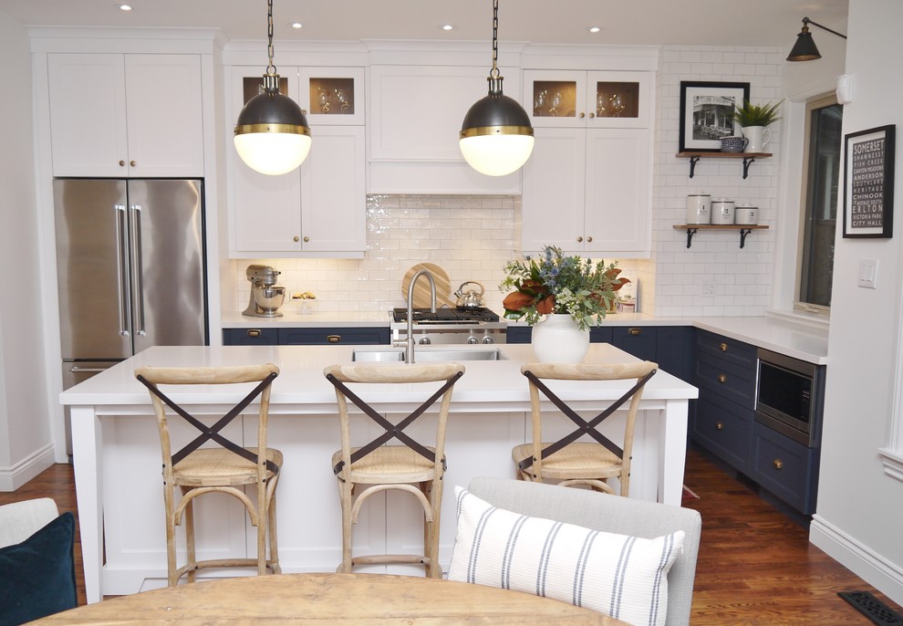 Eat-in kitchen - mid-sized transitional l-shaped medium tone wood floor and brown floor eat-in kitchen idea in Toronto with an undermount sink, shaker cabinets, blue cabinets, quartz countertops, white backsplash, subway tile backsplash, stainless steel appliances, an island and white countertops