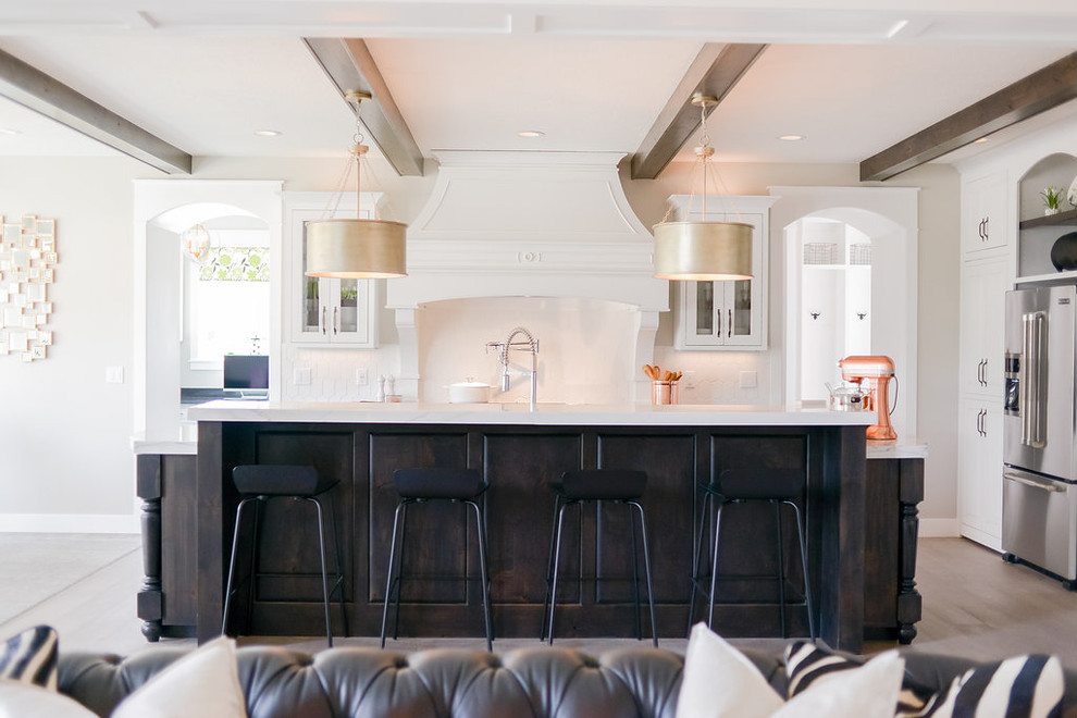 Inspiration for a mid-sized transitional l-shaped light wood floor and gray floor eat-in kitchen remodel in Seattle with a farmhouse sink, raised-panel cabinets, white cabinets, marble countertops, white backsplash, subway tile backsplash, stainless steel appliances and an island