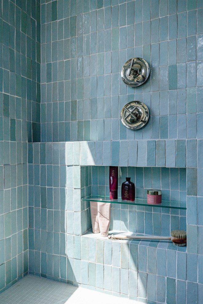 Cette photo montre une douche en alcôve principale chic de taille moyenne avec un carrelage bleu, un mur bleu, un sol blanc, une cabine de douche à porte battante et une niche.