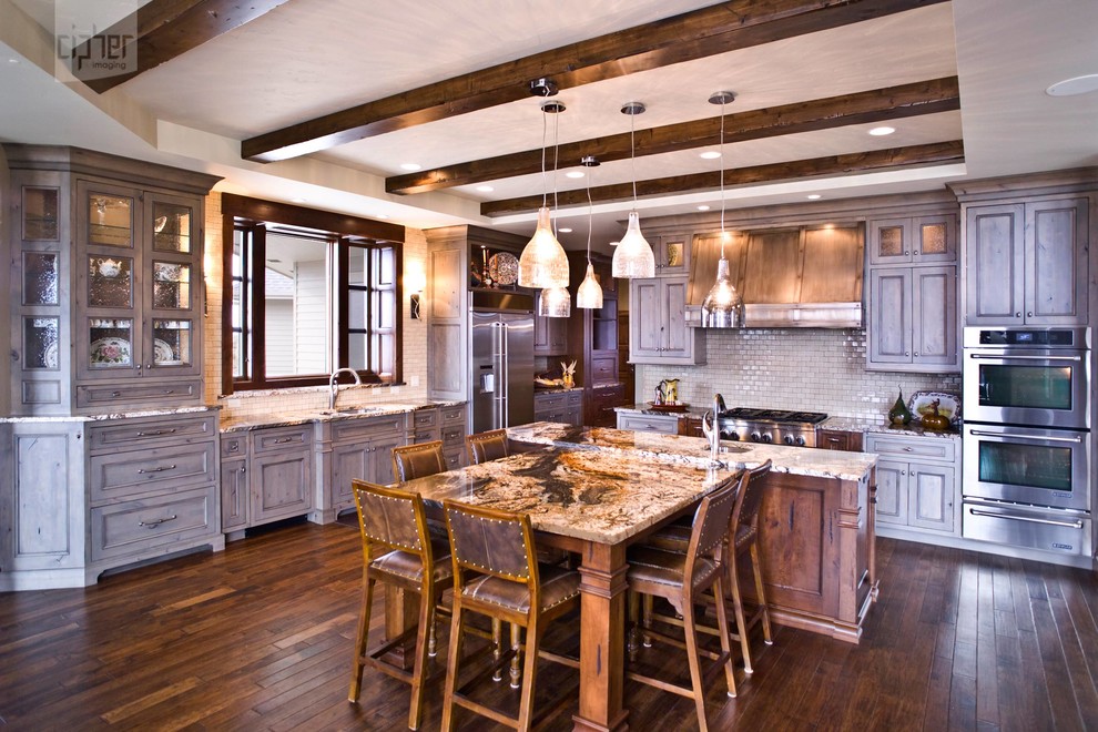 Example of a large transitional l-shaped dark wood floor and brown floor eat-in kitchen design with an undermount sink, recessed-panel cabinets, beige backsplash, porcelain backsplash, stainless steel appliances, beige walls, an island, gray cabinets and granite countertops