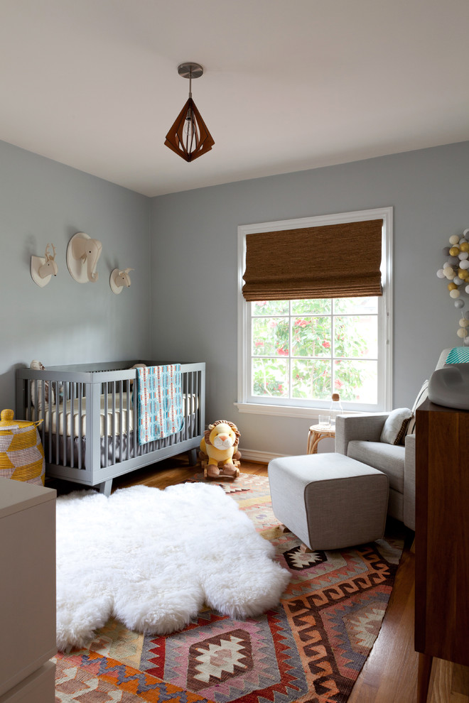 This is an example of a contemporary gender-neutral nursery in Los Angeles with grey walls.