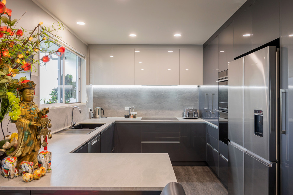 Bild på ett litet funkis grå grått u-kök, med en dubbel diskho, släta luckor, grå skåp, stänkskydd i porslinskakel, rostfria vitvaror, vinylgolv, en halv köksö och grått golv