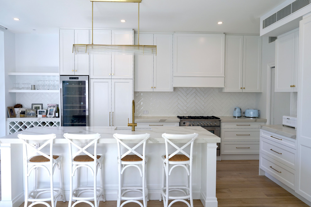 Idéer för ett stort klassiskt vit kök, med en undermonterad diskho, luckor med infälld panel, vita skåp, bänkskiva i kvarts, vitt stänkskydd, stänkskydd i keramik, rostfria vitvaror, mellanmörkt trägolv, en köksö och brunt golv