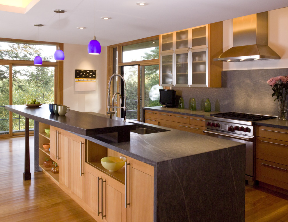 Contemporary kitchen in Boston with stainless steel appliances, an undermount sink, glass-front cabinets, medium wood cabinets, grey splashback and stone slab splashback.