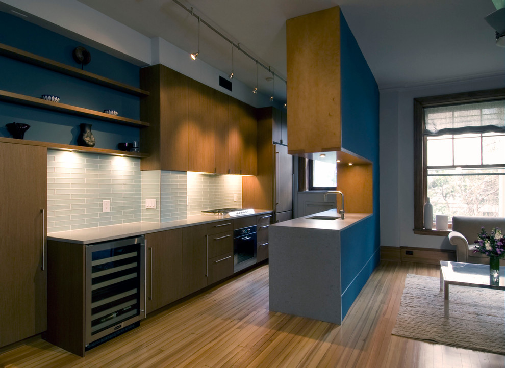 Photo of a contemporary galley eat-in kitchen in DC Metro with flat-panel cabinets, medium wood cabinets, glass tile splashback, coloured appliances, a peninsula, a single-bowl sink and blue splashback.