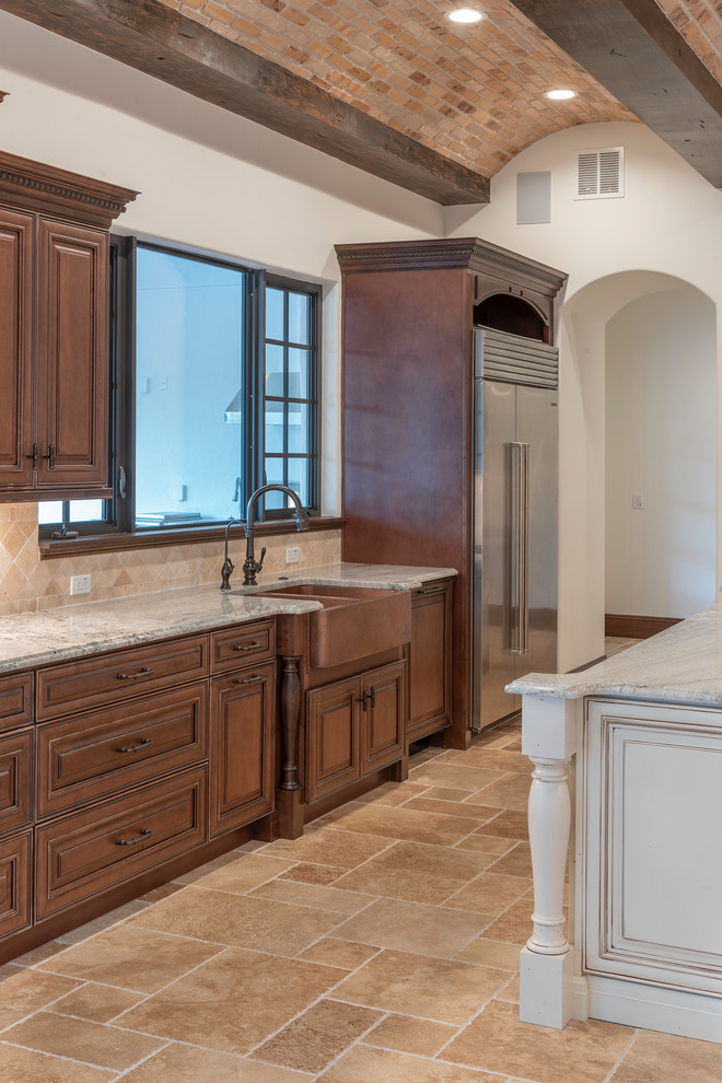 Inspiration for a large mediterranean kitchen pantry in Orlando with a farmhouse sink, raised-panel cabinets, dark wood cabinets, granite benchtops, beige splashback, stone tile splashback, stainless steel appliances, travertine floors, with island, beige floor and grey benchtop.