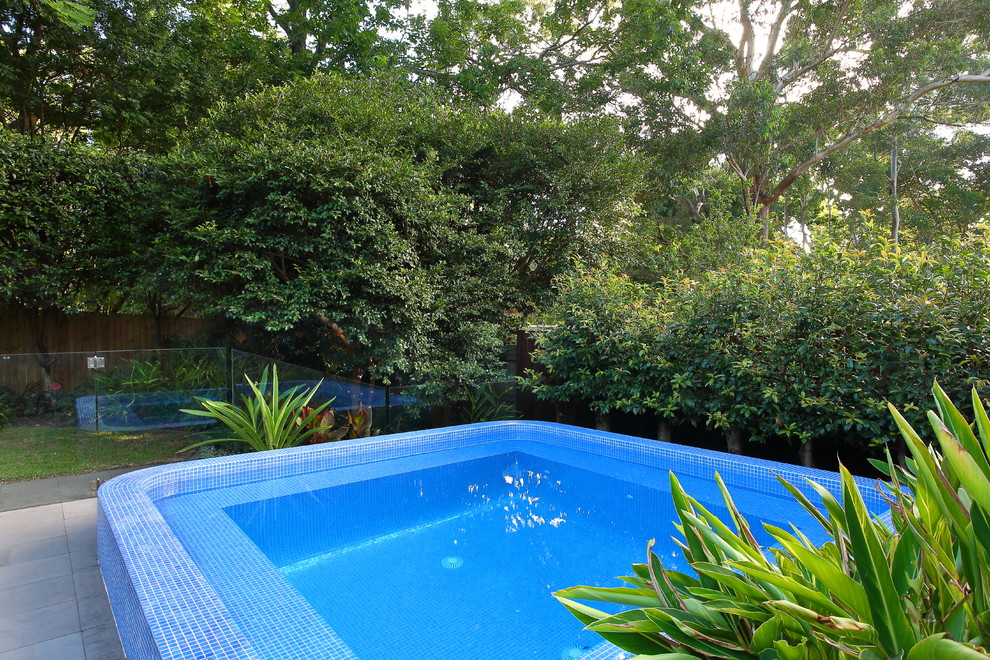 Small modern backyard rectangular pool in Sydney with natural stone pavers.
