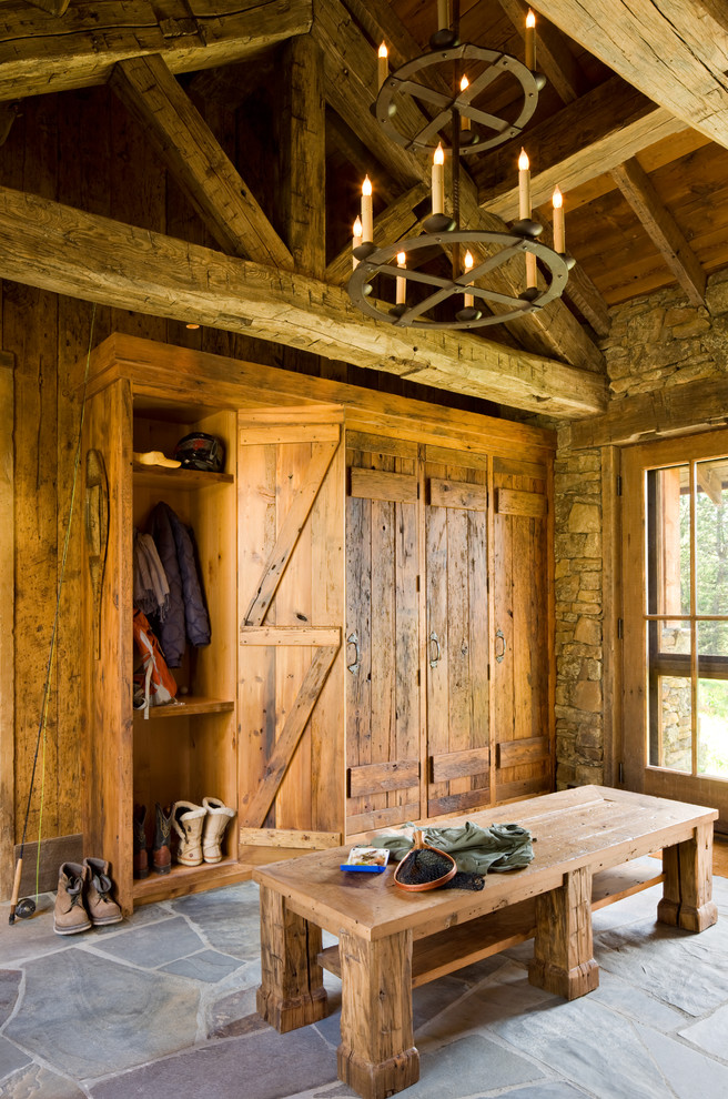 Example of a mountain style mudroom design with a glass front door