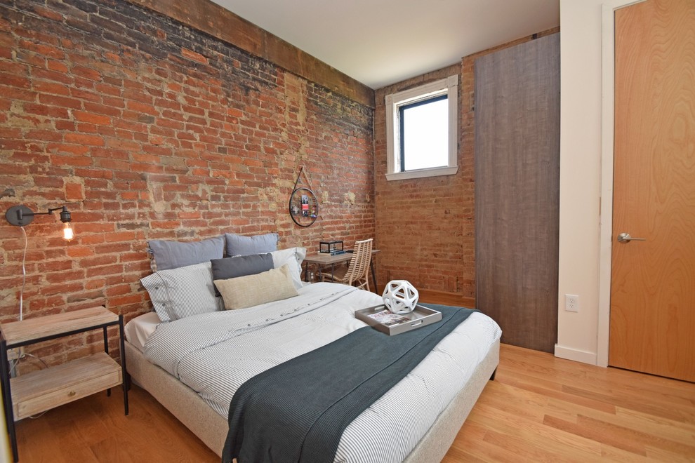 Photo of a mid-sized industrial loft-style bedroom in Cincinnati with brown walls, light hardwood floors, no fireplace and beige floor.