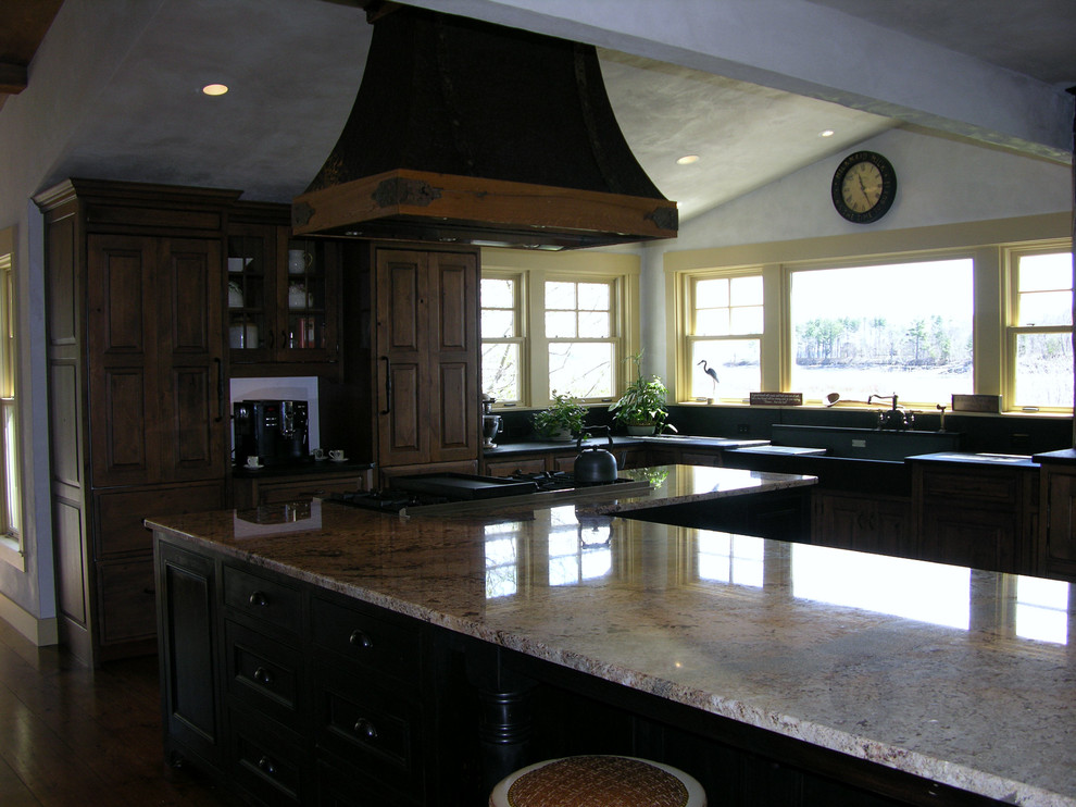 Design ideas for an expansive country u-shaped open plan kitchen in Portland Maine with a farmhouse sink, beaded inset cabinets, dark wood cabinets, granite benchtops, black splashback, stone slab splashback, panelled appliances, medium hardwood floors and with island.