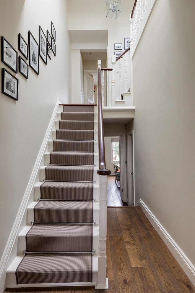 Design ideas for a mid-sized traditional carpeted l-shaped staircase in London with carpet risers and wood railing.