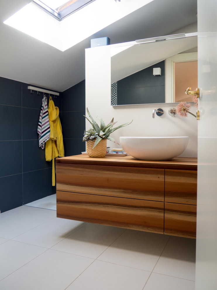 Idéer för mellanstora eklektiska badrum med dusch, med släta luckor, skåp i mörkt trä, en dusch i en alkov, en toalettstol med separat cisternkåpa, blå kakel, cementkakel, klinkergolv i porslin, ett fristående handfat, träbänkskiva och vitt golv