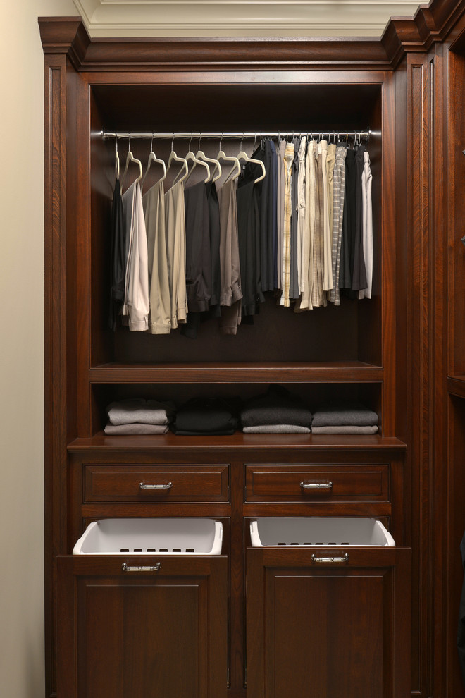 This is an example of a mid-sized traditional men's walk-in wardrobe in New York with raised-panel cabinets, dark wood cabinets, carpet and beige floor.