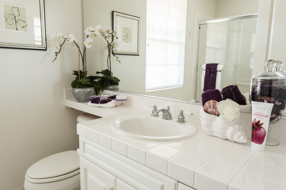 Design ideas for a mid-sized transitional kids bathroom in Orange County with a drop-in sink, beaded inset cabinets, white cabinets, an alcove tub, an alcove shower, a two-piece toilet, white tile and white walls.
