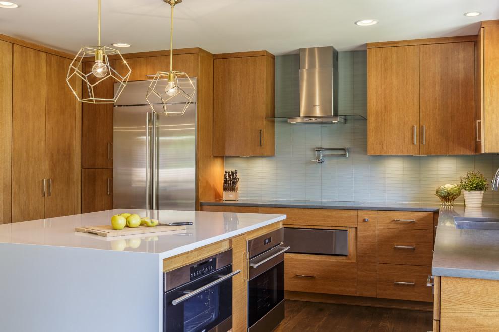 Mid-sized modern l-shaped eat-in kitchen in Kansas City with an undermount sink, flat-panel cabinets, medium wood cabinets, quartz benchtops, blue splashback, stainless steel appliances, dark hardwood floors, with island and white benchtop.