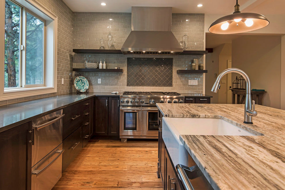 Inspiration for a large transitional l-shaped medium tone wood floor and brown floor open concept kitchen remodel with a farmhouse sink, shaker cabinets, dark wood cabinets, granite countertops, gray backsplash, subway tile backsplash, paneled appliances and an island