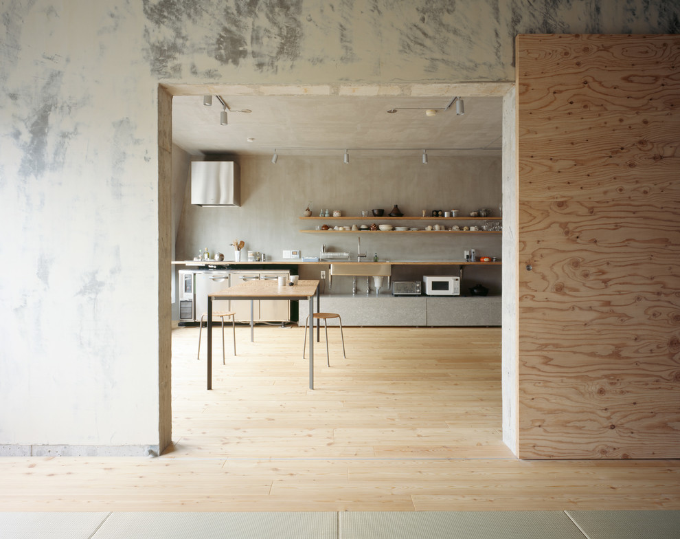 Industrial dining room in Tokyo with grey walls, light hardwood floors and brown floor.
