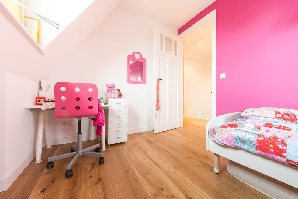 This is an example of a small traditional loft-style bedroom in Toronto with pink walls and light hardwood floors.