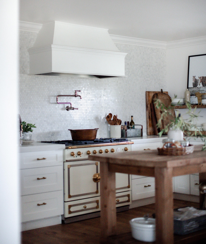 Bild på ett mellanstort 50 tals vit vitt u-kök, med en rustik diskho, skåp i shakerstil, vita skåp, vitt stänkskydd, stänkskydd i mosaik, vita vitvaror och en halv köksö