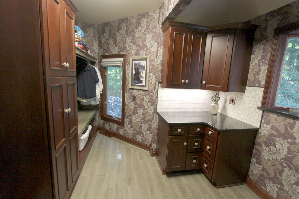 This is an example of a mid-sized traditional u-shaped dedicated laundry room in Cleveland with a single-bowl sink, flat-panel cabinets, medium wood cabinets, granite benchtops, multi-coloured walls, medium hardwood floors and a stacked washer and dryer.