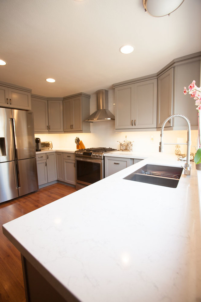 Eat-in kitchen - large transitional u-shaped dark wood floor eat-in kitchen idea in Los Angeles with an undermount sink, recessed-panel cabinets, gray cabinets, quartz countertops, white backsplash, subway tile backsplash, stainless steel appliances and no island