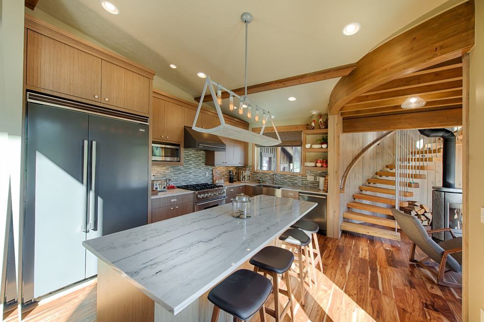 Inspiration for a mid-sized country l-shaped kitchen in Boise with a farmhouse sink, flat-panel cabinets, light wood cabinets, marble benchtops, grey splashback, ceramic splashback, stainless steel appliances, medium hardwood floors and with island.