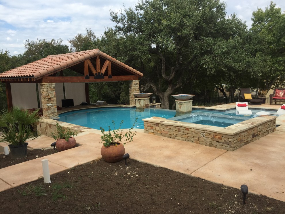 Inspiration for a large rustic backyard custom-shaped infinity hot tub remodel in Austin with decking