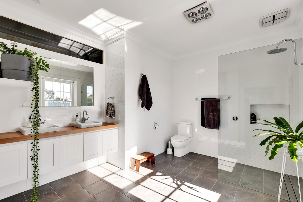 Large contemporary master bathroom in Adelaide with shaker cabinets, white cabinets, an open shower, a wall-mount toilet, white tile, porcelain floors, a drop-in sink, wood benchtops, grey floor, an open shower, a niche and a floating vanity.
