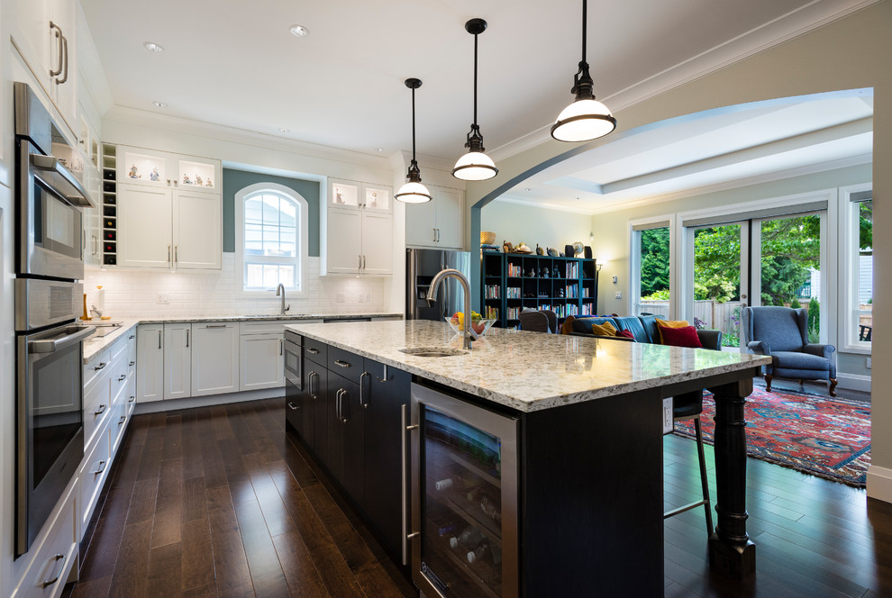Inspiration for a large transitional l-shaped dark wood floor open concept kitchen remodel in Vancouver with an undermount sink, shaker cabinets, white cabinets, quartz countertops, white backsplash, subway tile backsplash, stainless steel appliances and an island