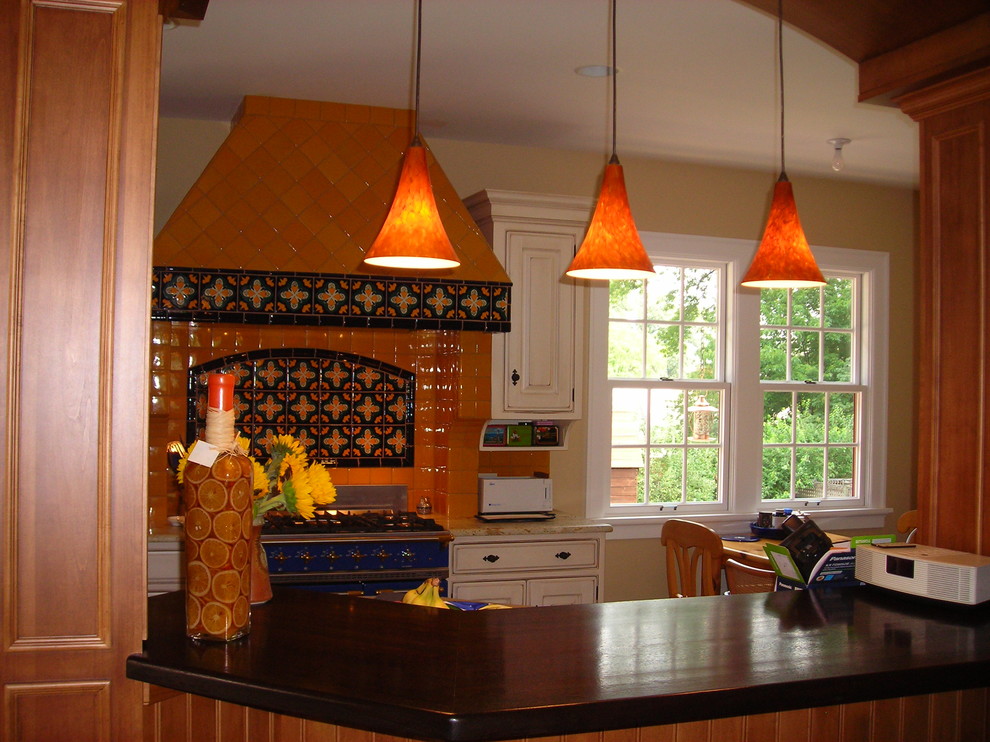 Photo of a mid-sized mediterranean single-wall eat-in kitchen in Sacramento with raised-panel cabinets, white cabinets, multi-coloured splashback, ceramic splashback, coloured appliances, with island and black benchtop.