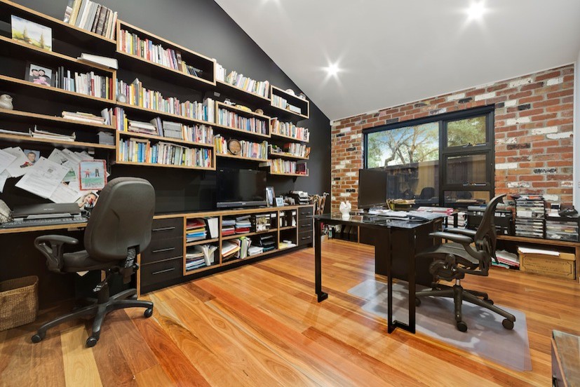 Photo of a mid-sized contemporary study room in Melbourne with black walls, light hardwood floors and a built-in desk.