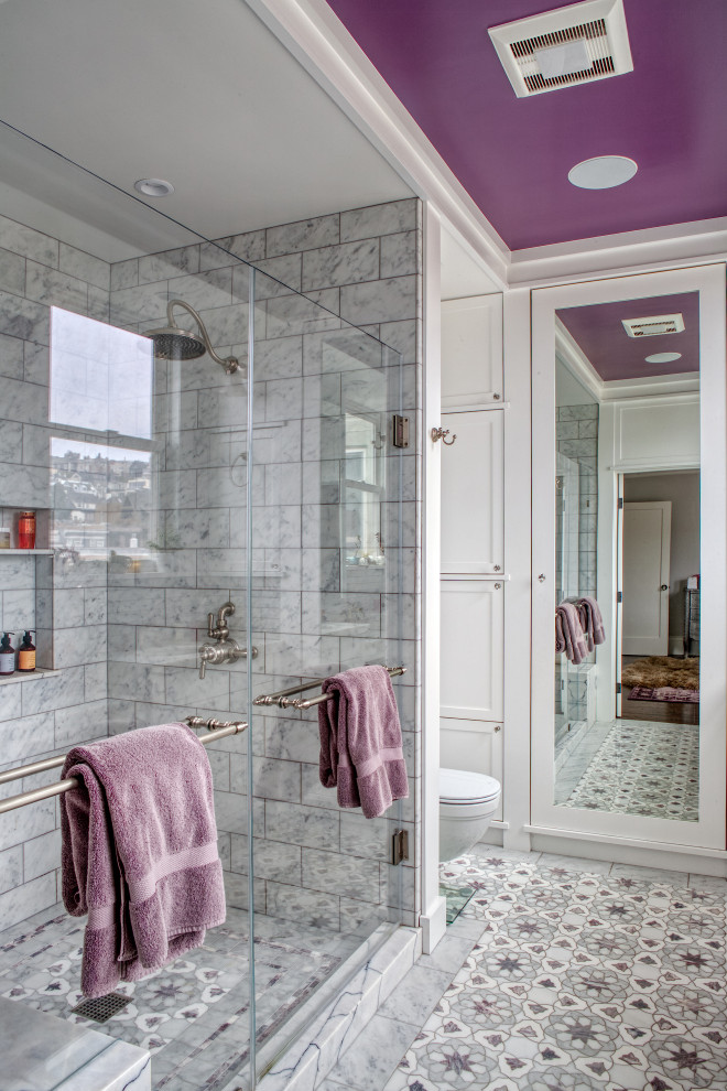 This is an example of a mid-sized traditional master bathroom in San Francisco with shaker cabinets, white cabinets, an alcove shower, a wall-mount toilet, white tile, stone tile, white walls, marble floors, an undermount sink, marble benchtops, purple floor, a hinged shower door, white benchtops, a double vanity, a built-in vanity, coffered and panelled walls.
