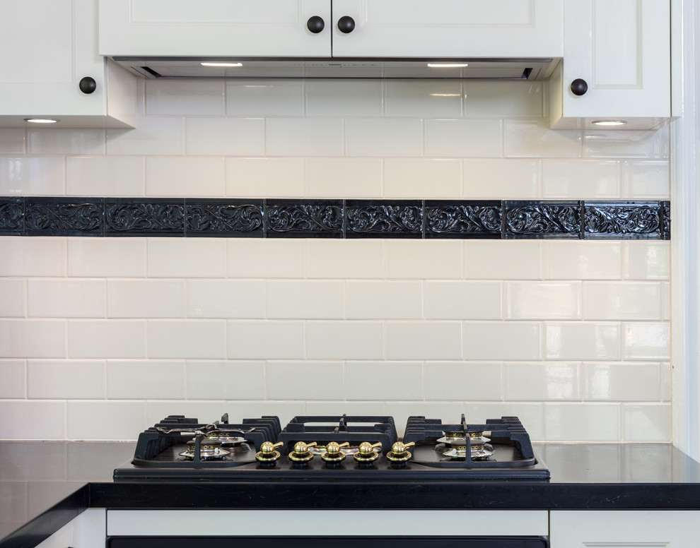 Photo of a traditional kitchen in Perth with shaker cabinets, white cabinets, quartz benchtops, white splashback, subway tile splashback, black appliances and black benchtop.
