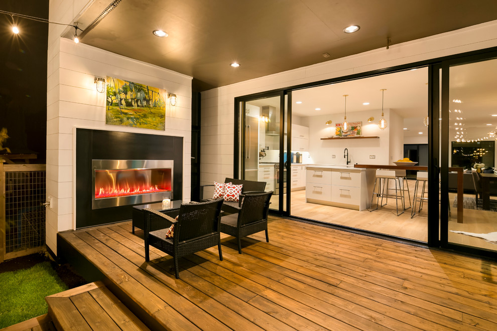 Inspiration for a contemporary backyard deck remodel in Seattle with a fireplace and a roof extension