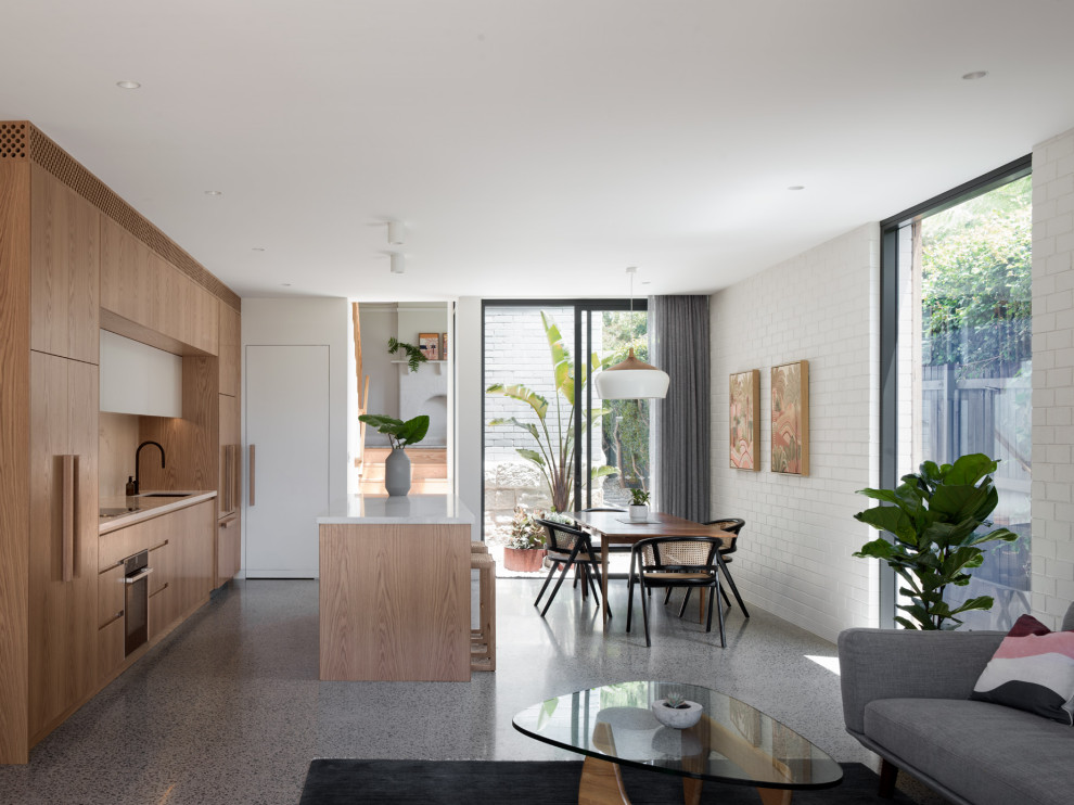 Contemporary galley open plan kitchen in Sydney with an undermount sink, flat-panel cabinets, light wood cabinets, concrete floors, with island, grey floor and white benchtop.